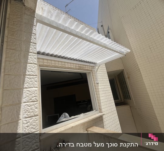 סוכך לבן מותקן מעל חלון חיצוני
